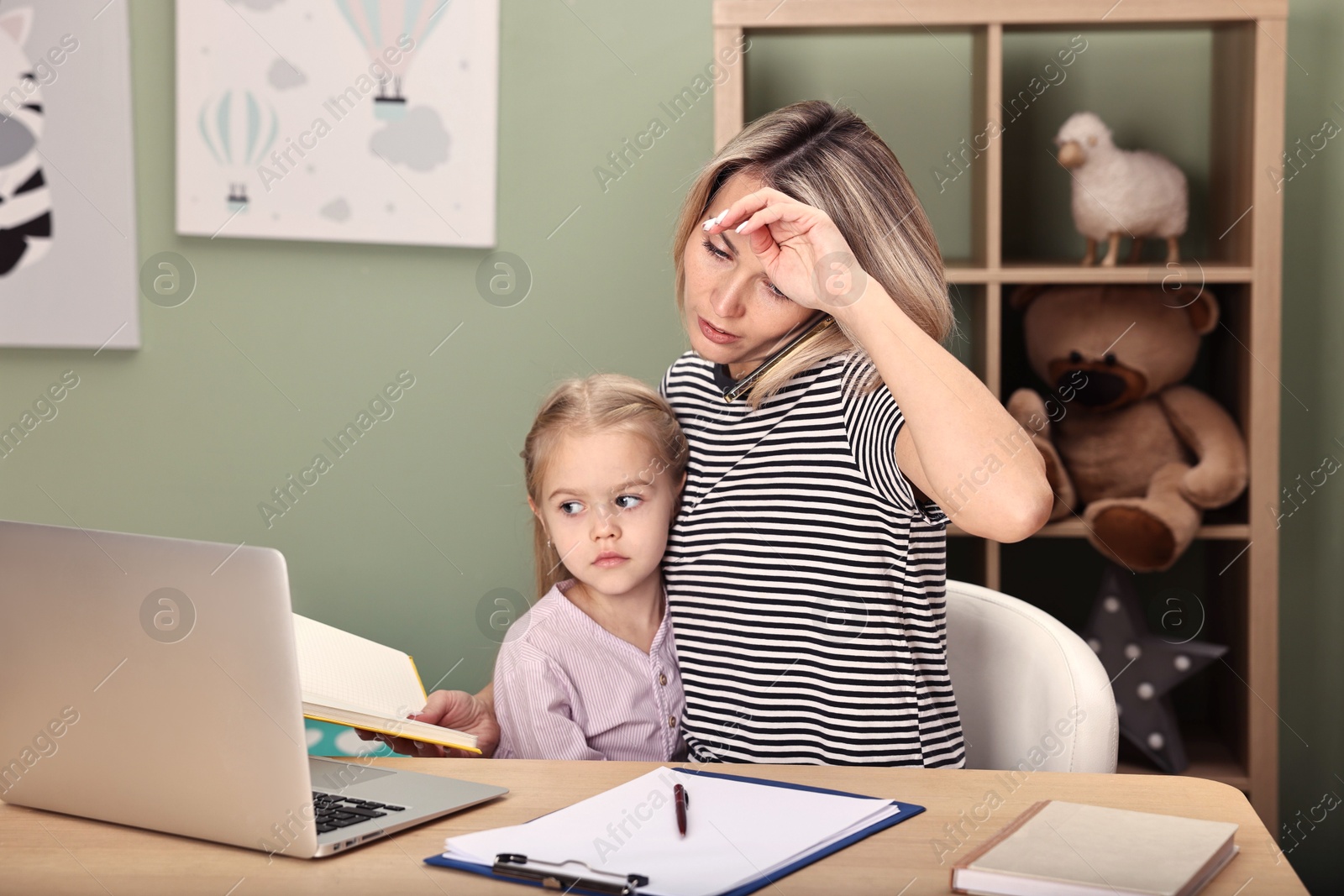 Photo of Work-family balance. Overwhelmed single mother talking by smartphone and her daughter at table in child's room