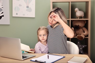 Photo of Work-family balance. Overwhelmed single mother talking by smartphone and her daughter at table in child's room