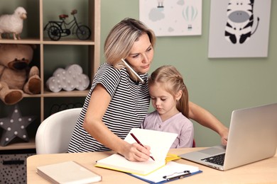 Photo of Work-family balance. Overwhelmed single mother talking by smartphone and her daughter at table in child's room