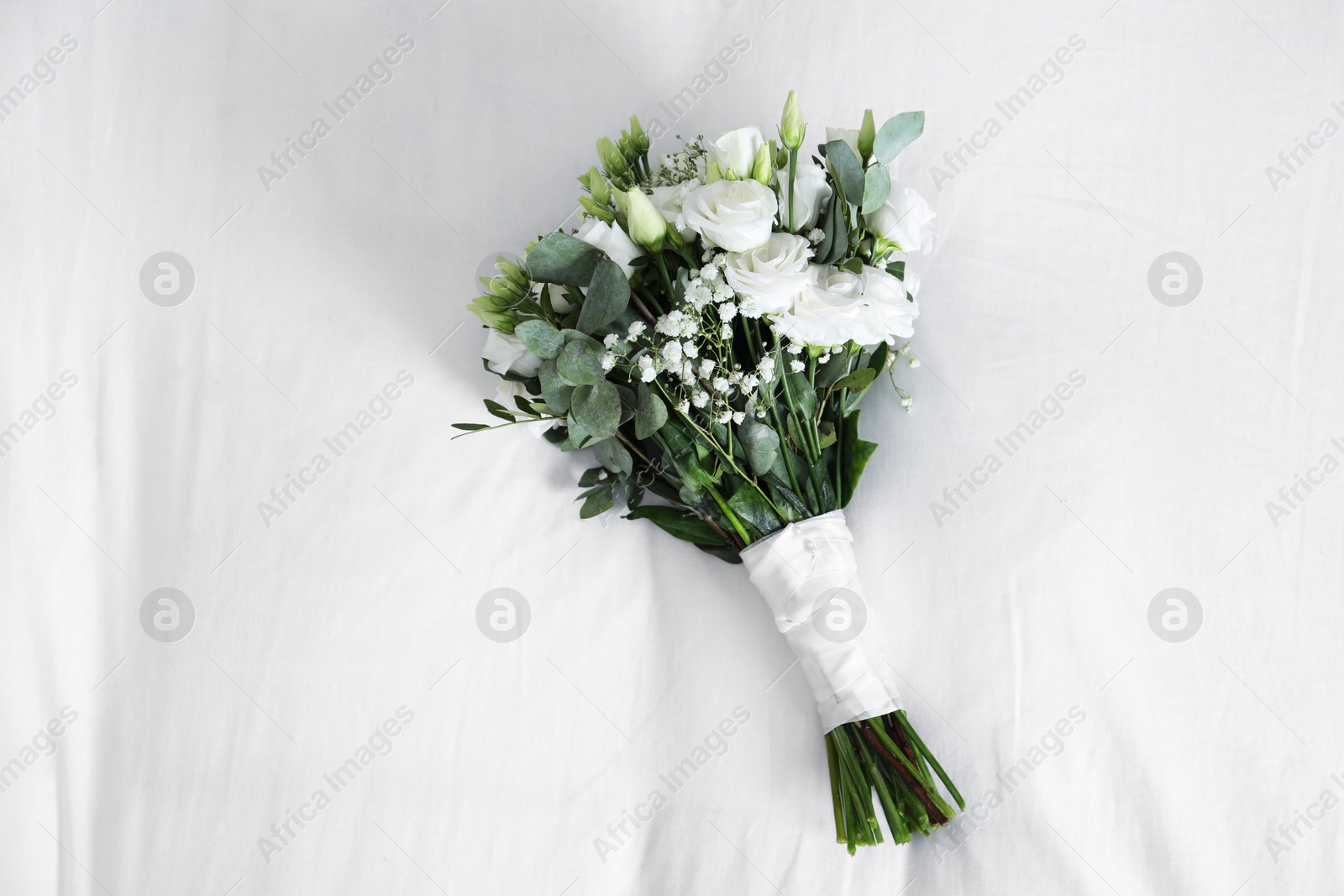 Photo of Wedding bouquet of beautiful flowers on linens, top view