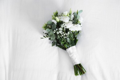 Photo of Wedding bouquet of beautiful flowers on linens, top view