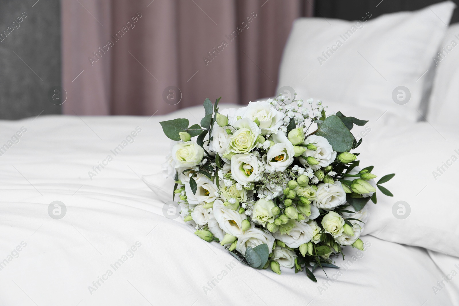 Photo of Wedding bouquet of beautiful flowers on bed indoors, closeup. Space for text