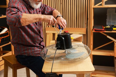 Photo of Relaxing hobby. Senior man repairing fan in workshop, closeup