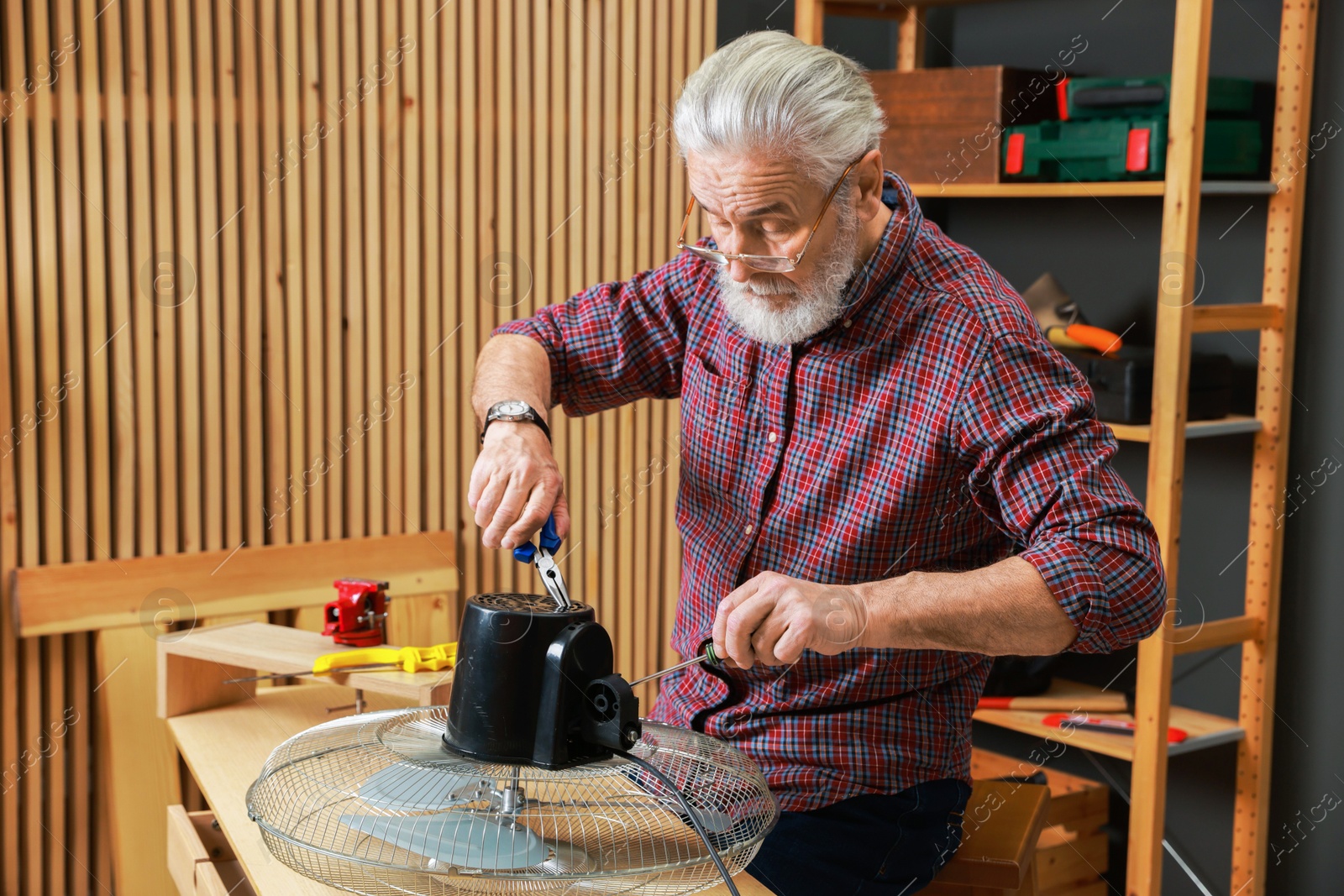 Photo of Relaxing hobby. Senior man repairing fan in workshop