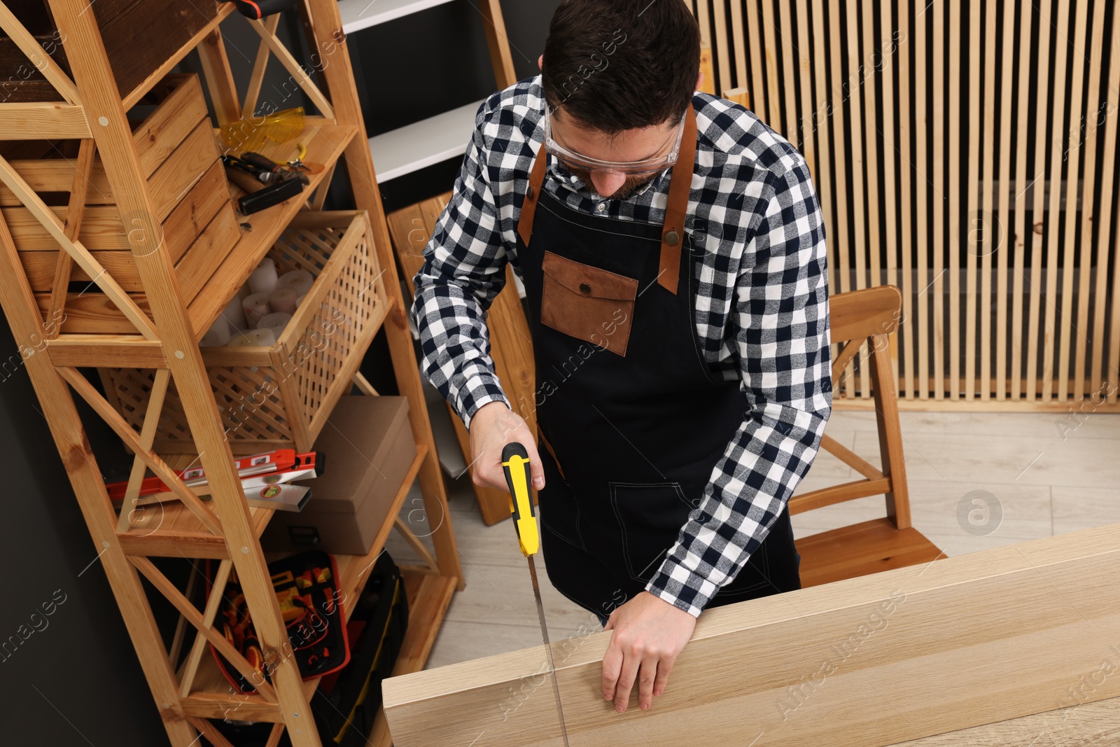 Photo of Relaxing hobby. Man sawing wooden plank at table in workshop