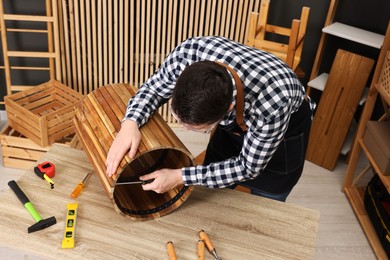 Photo of Relaxing hobby. Man assembling wooden trash can with screwdriver at table in workshop