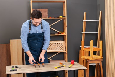 Photo of Relaxing hobby. Man with carpentry tools at table in workshop