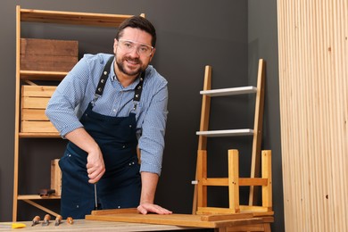 Photo of Relaxing hobby. Man working with wooden plank and screwdriver at table in workshop