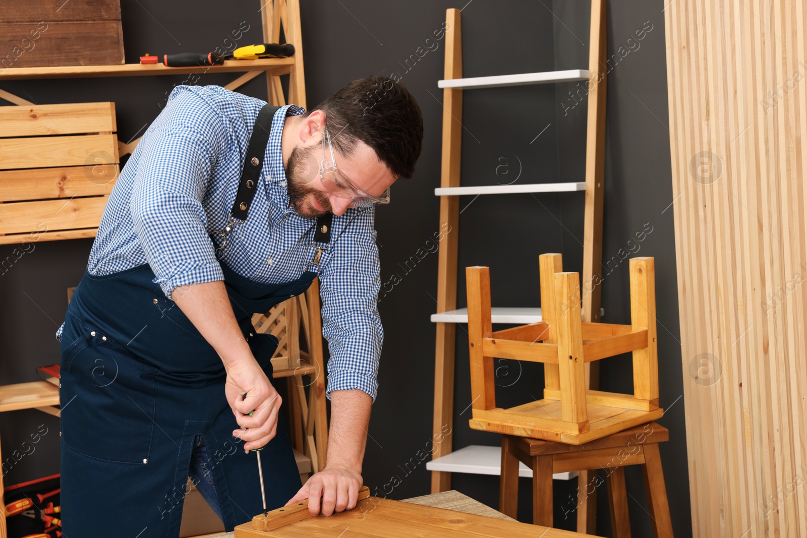 Photo of Relaxing hobby. Man working with wooden plank and screwdriver at table in workshop