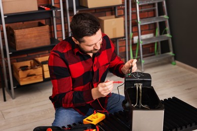 Photo of Relaxing hobby. Man testing deep fryer with multimeter in workshop