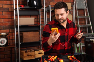 Photo of Relaxing hobby. Man testing deep fryer with multimeter in workshop