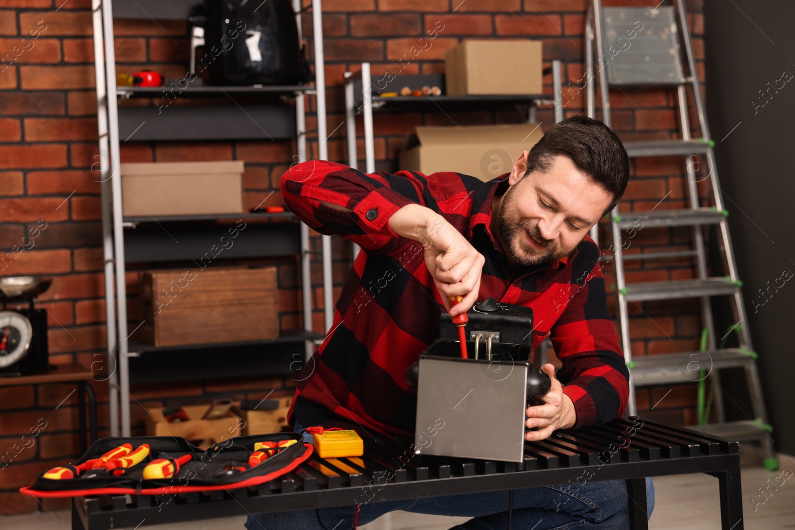 Photo of Relaxing hobby. Man testing deep fryer with multimeter in workshop