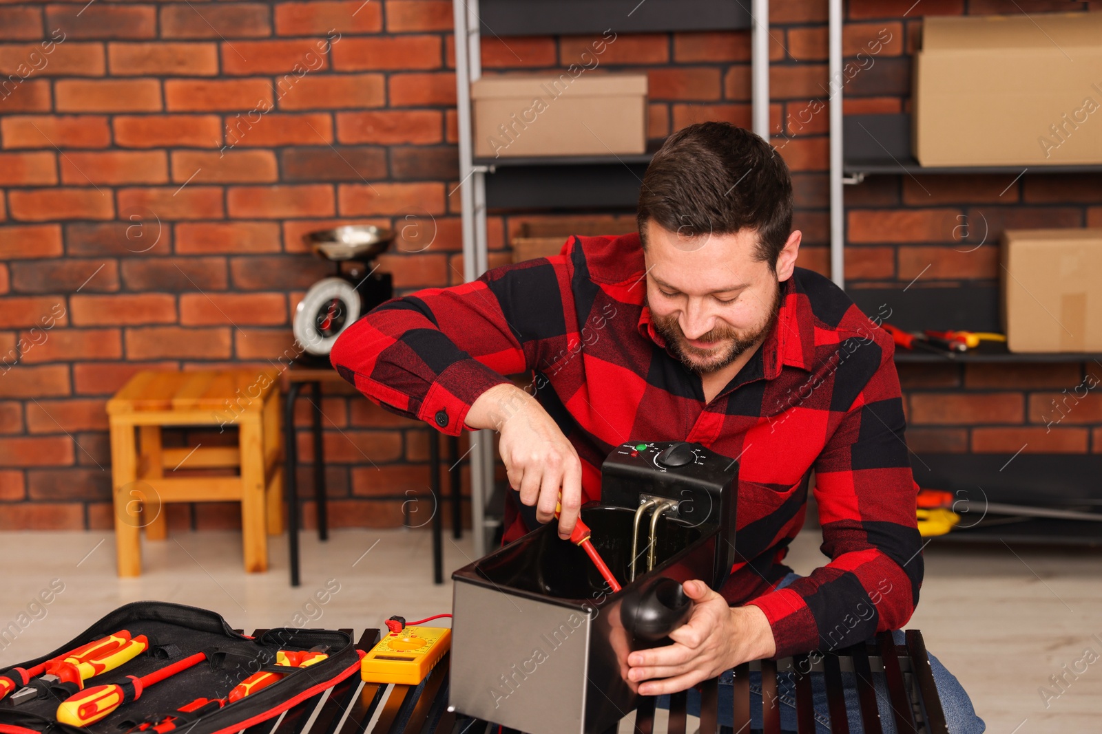 Photo of Relaxing hobby. Man testing deep fryer with multimeter in workshop