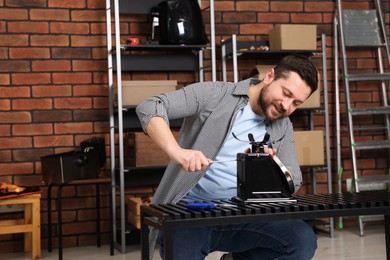 Photo of Relaxing hobby. Man repairing mechanical kitchen scale with screwdriver in workshop