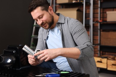 Photo of Relaxing hobby. Man examining parts of electric meat grinder in workshop