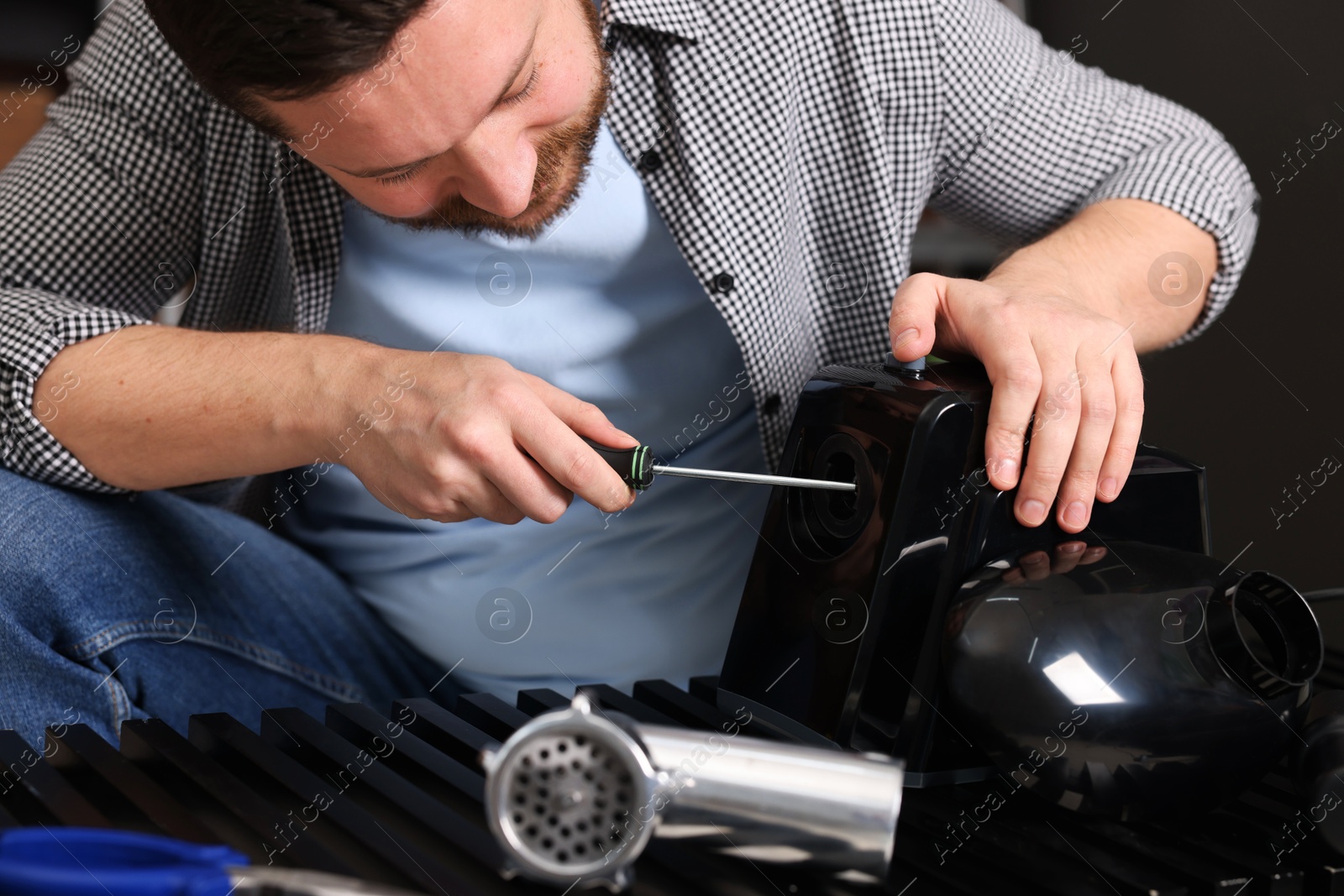 Photo of Relaxing hobby. Man repairing electric meat grinder indoors