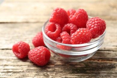 Photo of Tasty raspberries in glass bowl on wooden table, closeup