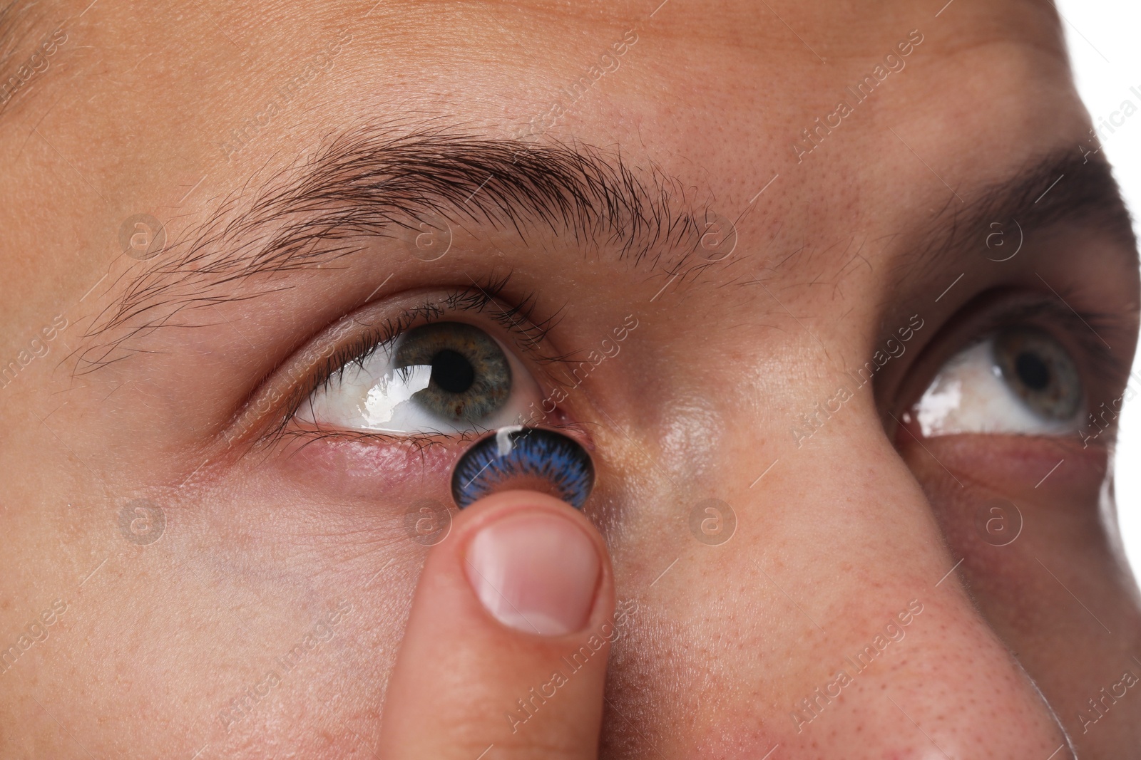 Photo of Man putting color contact lens in his eye, closeup