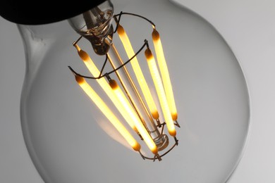 Photo of Glowing light bulb on grey background, closeup