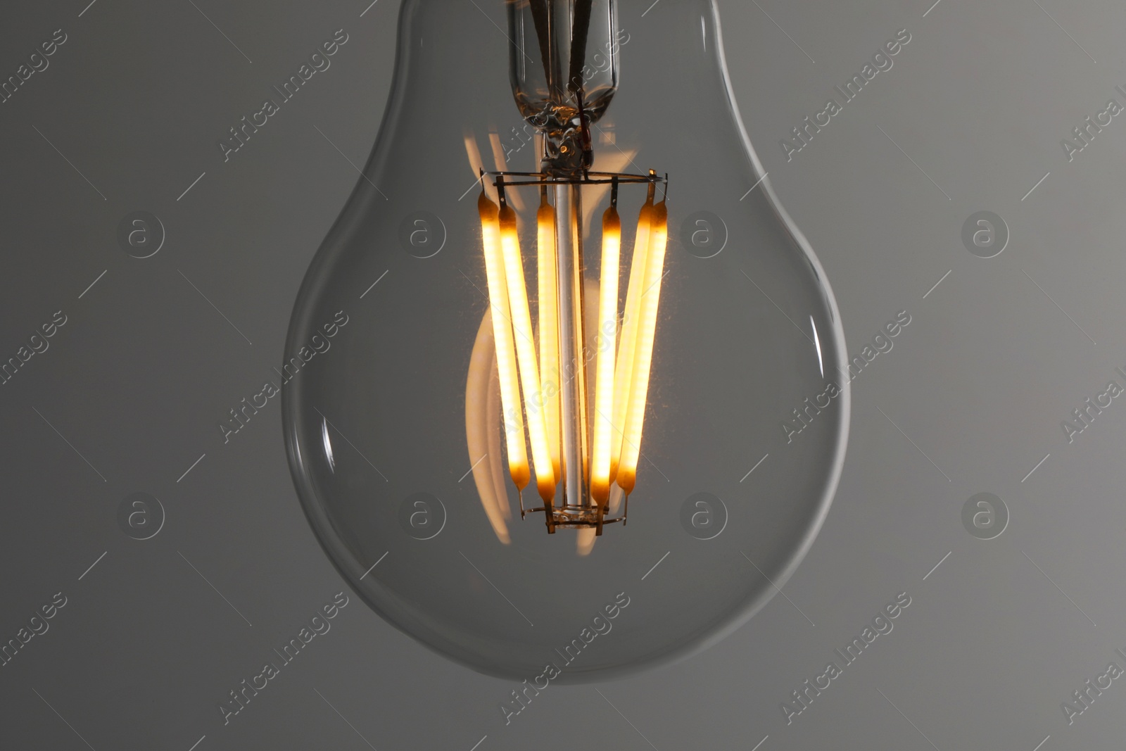 Photo of Glowing light bulb on grey background, closeup