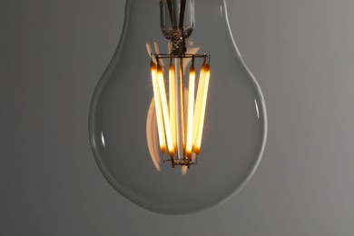 Photo of Glowing light bulb on grey background, closeup