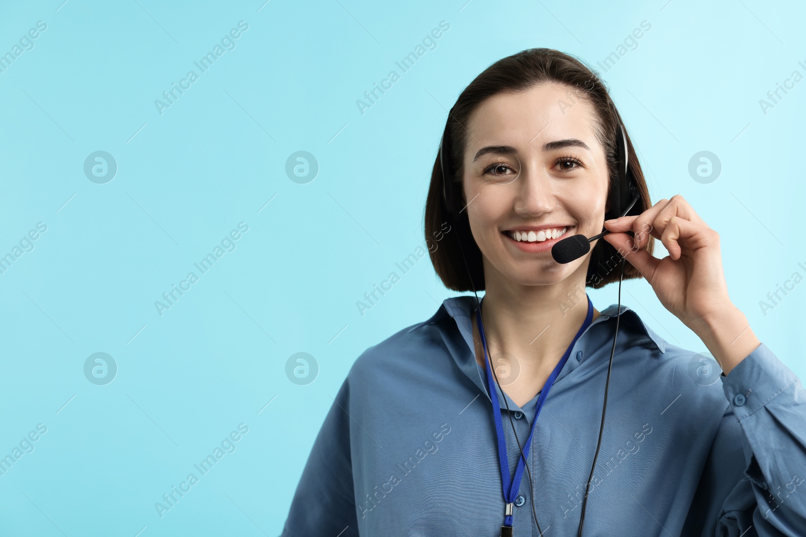 Photo of Technical support call center. Smiling operator on light blue background. Space for text