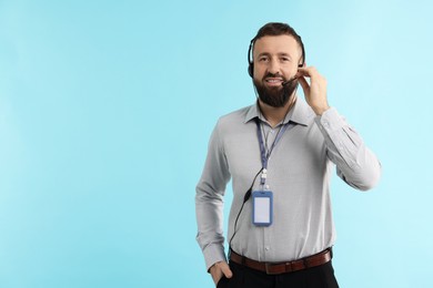 Photo of Technical support call center. Smiling operator on light blue background. Space for text