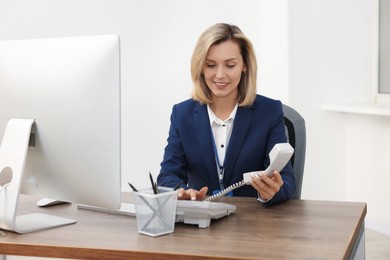 Photo of Technical support call center. Smiling operator working at table in office