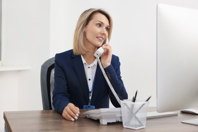 Photo of Technical support call center. Smiling operator working at table in office