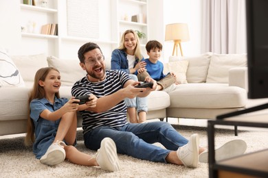 Photo of Happy family playing video games in living room