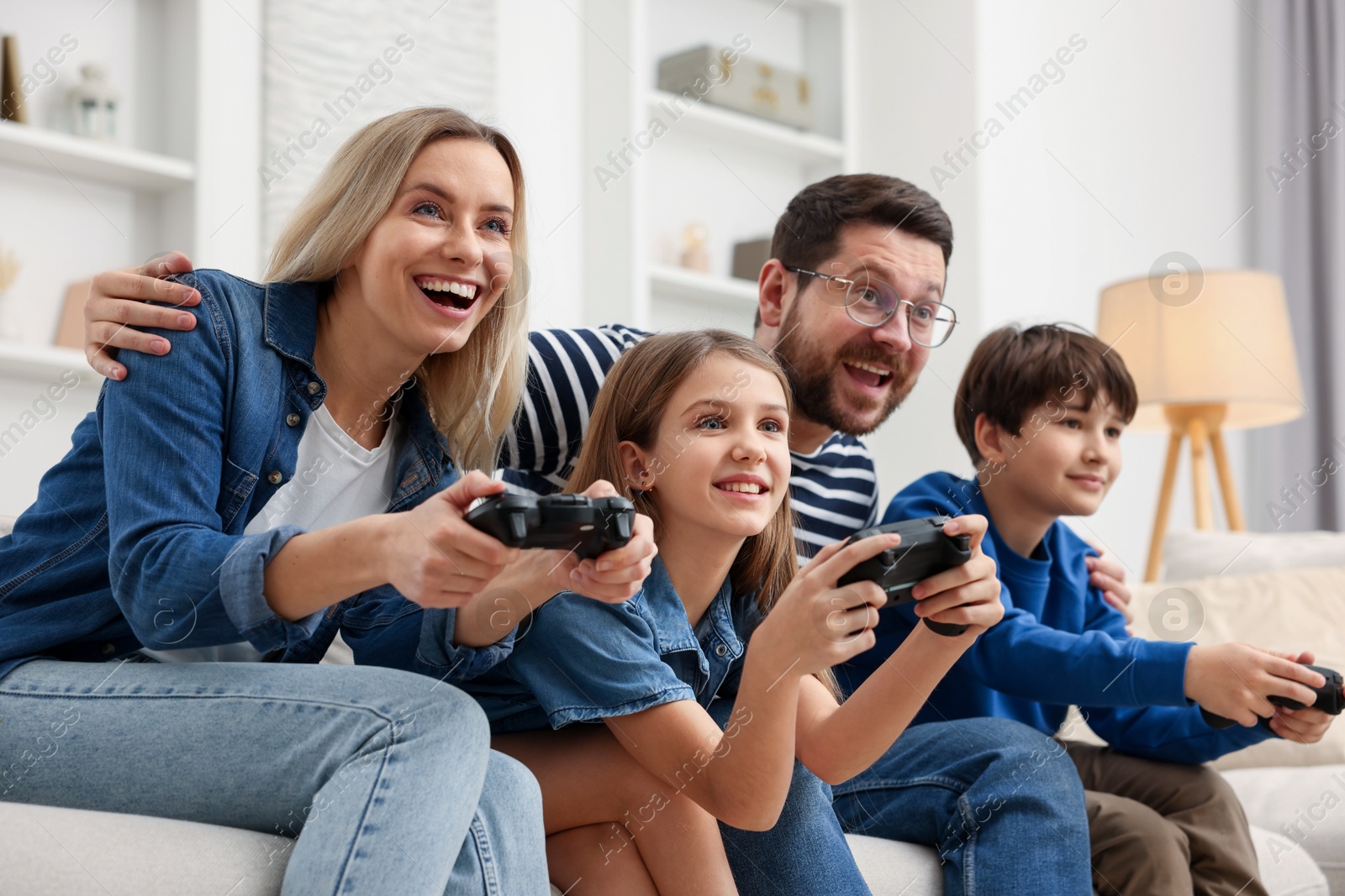 Photo of Happy family playing video games on sofa in living room