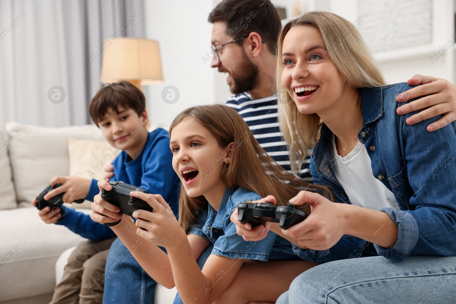 Photo of Happy family playing video games on sofa at home, selective focus