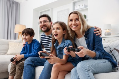 Photo of Happy family playing video games on sofa in living room