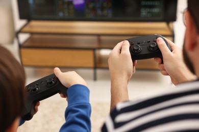 Photo of Father and his son playing video games at home, closeup