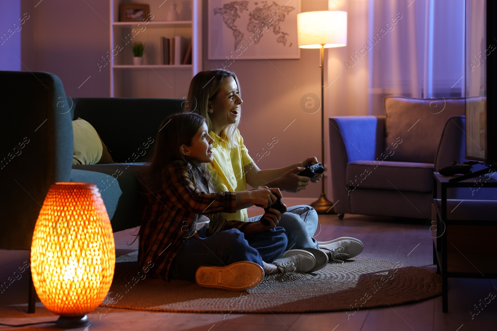 Photo of Happy mother and her daughter playing video games at home