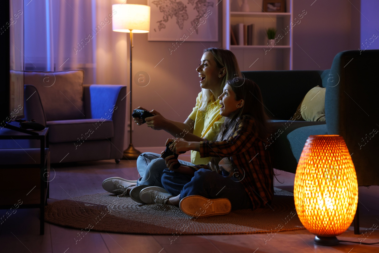 Photo of Happy mother and her daughter playing video games at home