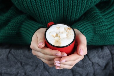 Photo of Woman holding mug of tasty hot chocolate with marshmallows, closeup