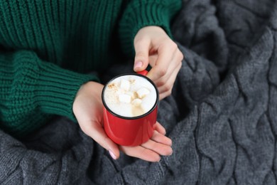 Photo of Woman holding mug of tasty hot chocolate with marshmallows, closeup