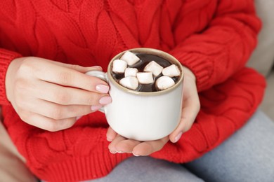 Photo of Woman holding mug of tasty hot chocolate with marshmallows, closeup