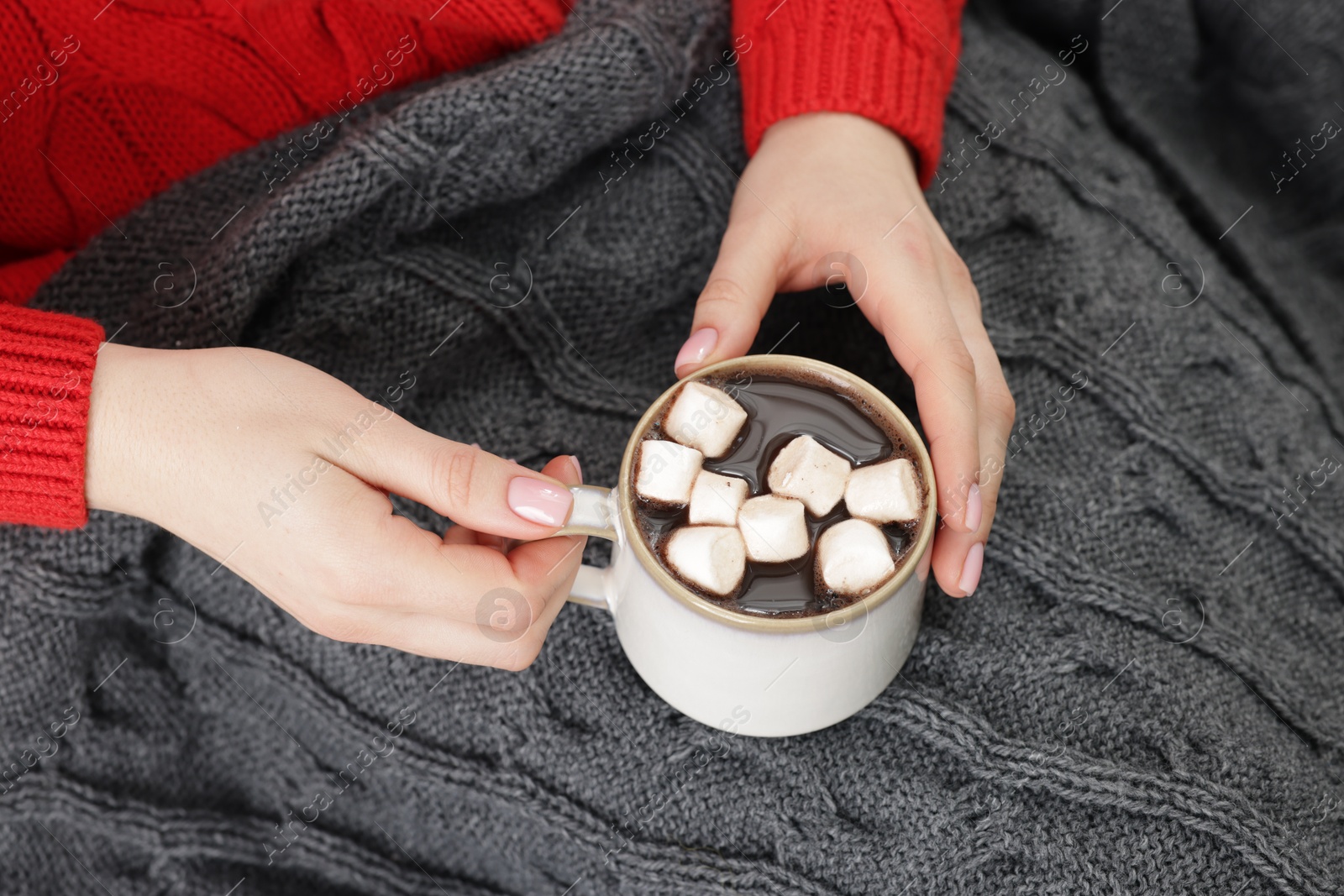 Photo of Woman holding mug of tasty hot chocolate with marshmallows, closeup