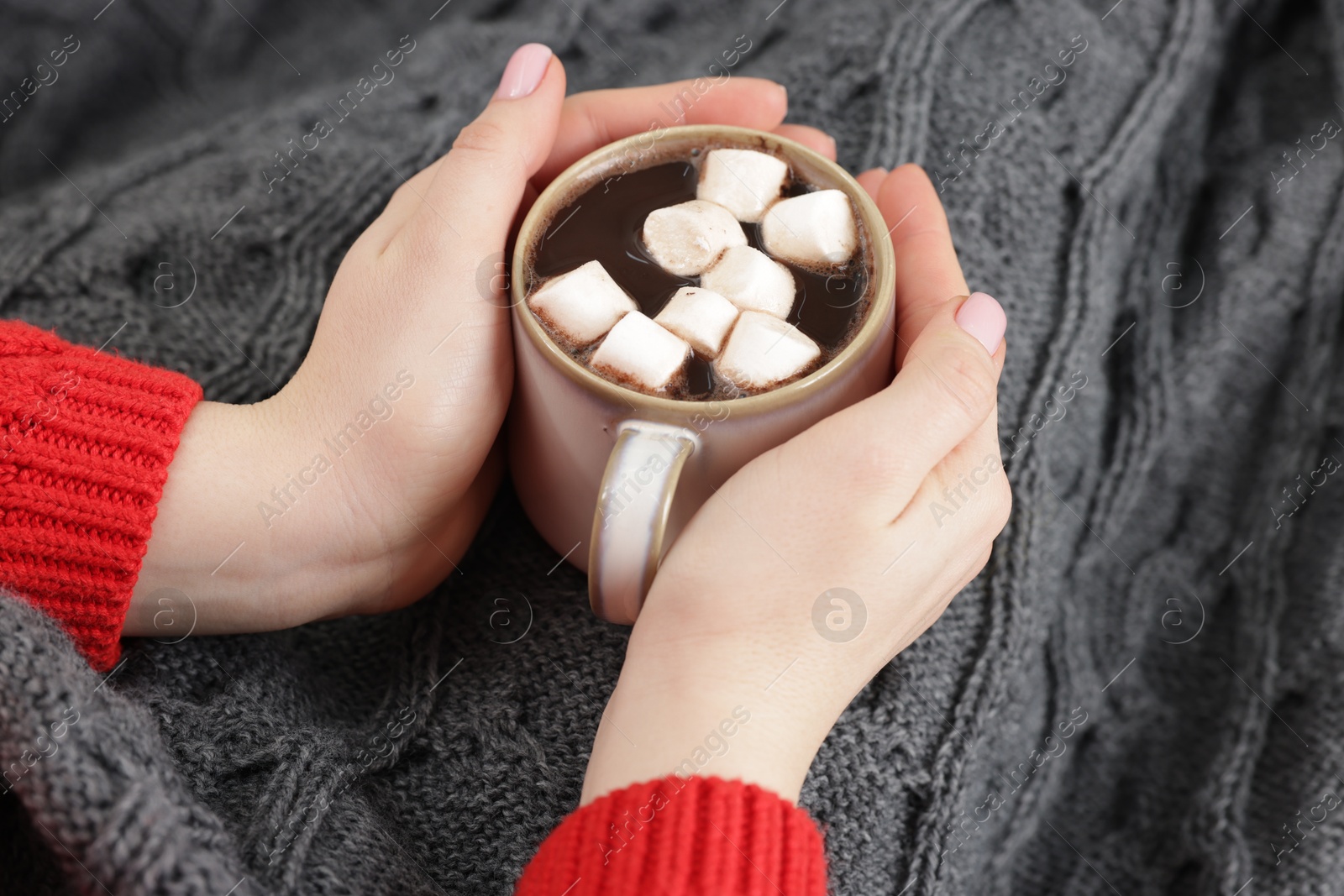 Photo of Woman holding mug of tasty hot chocolate with marshmallows, closeup