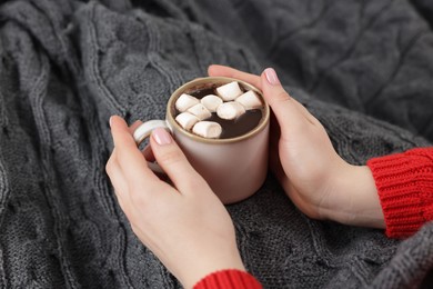 Photo of Woman holding mug of tasty hot chocolate with marshmallows, closeup