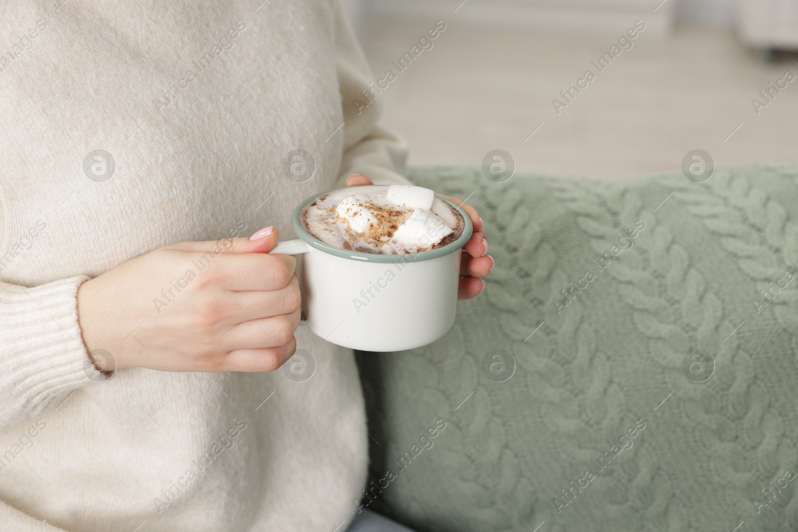 Photo of Woman holding mug of tasty hot chocolate with marshmallows and cinnamon, closeup. Space for text