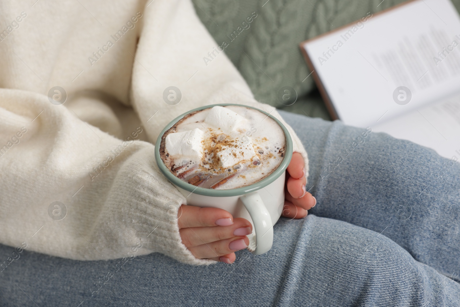 Photo of Woman holding mug of tasty hot chocolate with marshmallows and cinnamon, closeup