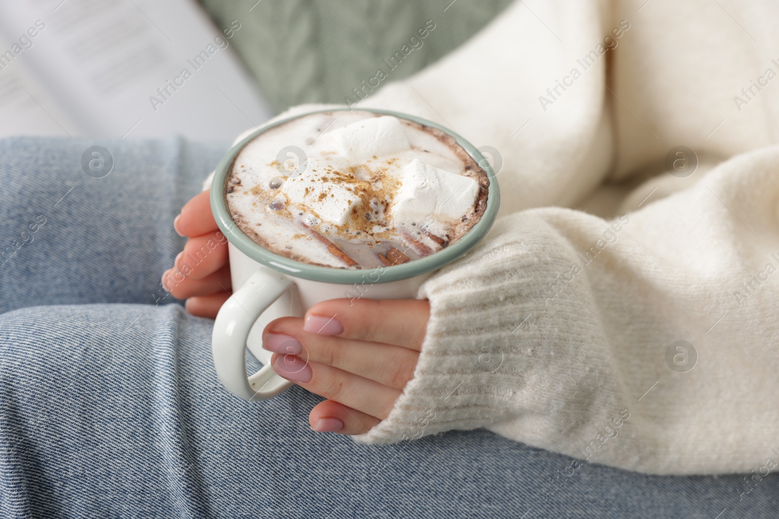 Photo of Woman holding mug of tasty hot chocolate with marshmallows and cinnamon, closeup