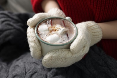 Photo of Woman holding mug of tasty hot chocolate with marshmallows and cinnamon, closeup