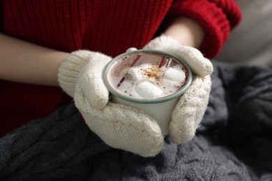 Photo of Woman holding mug of tasty hot chocolate with marshmallows and cinnamon, closeup