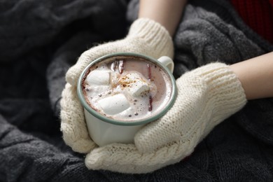 Photo of Woman holding mug of tasty hot chocolate with marshmallows and cinnamon, closeup