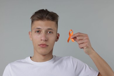 Photo of Multiple Sclerosis awareness. Man with orange ribbon on light grey background