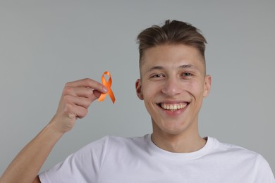 Photo of Multiple Sclerosis awareness. Man with orange ribbon on light grey background